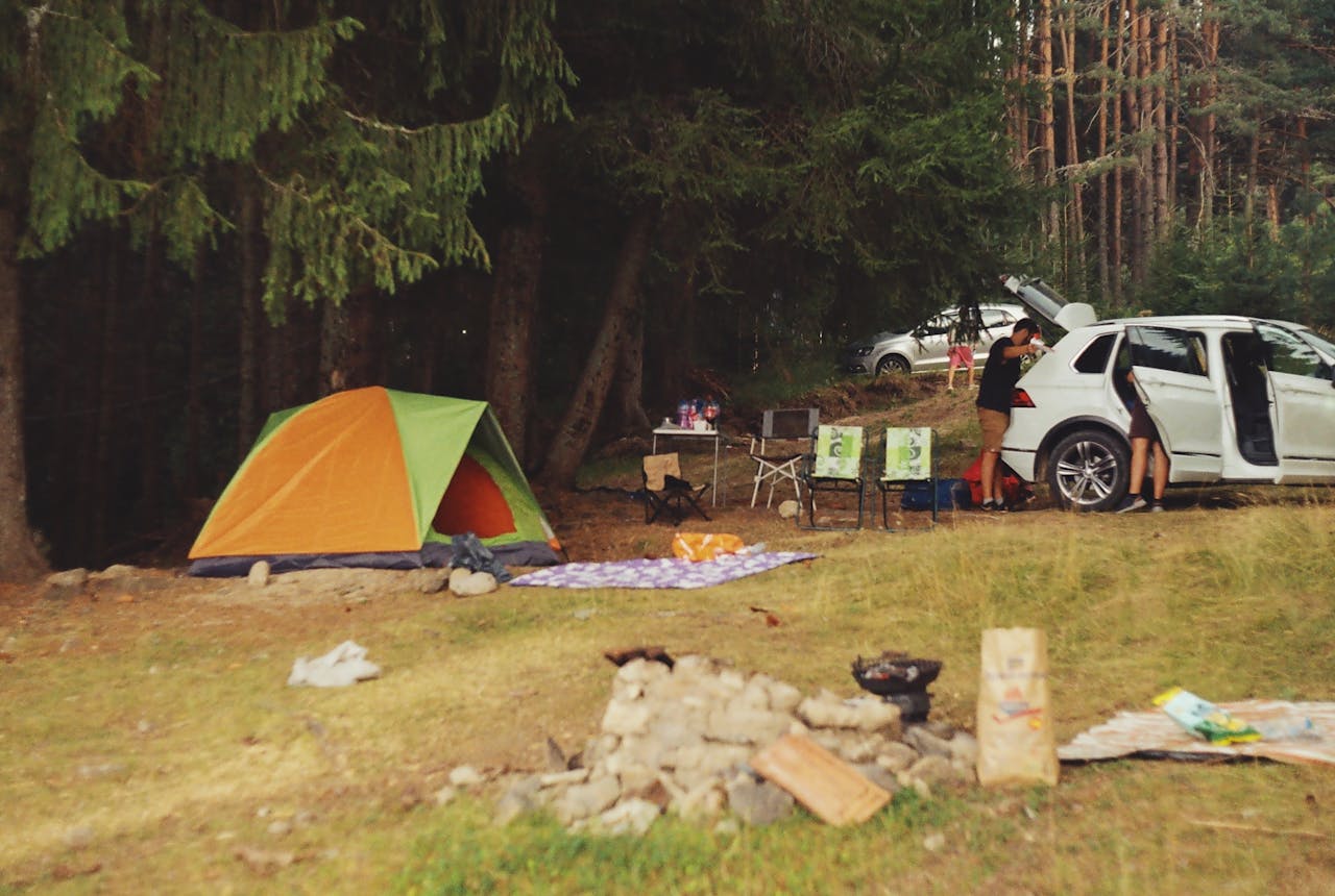 mobile-02 Explore a peaceful camping scene in the forest with a tent, car, and campfire setup.