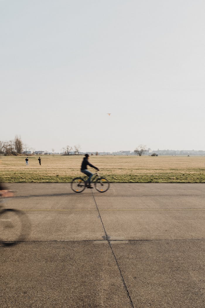 creative-02 Blurred motion shot of a cyclist riding through Tempelhofer Feld on a sunny day in Berlin, Germany.
