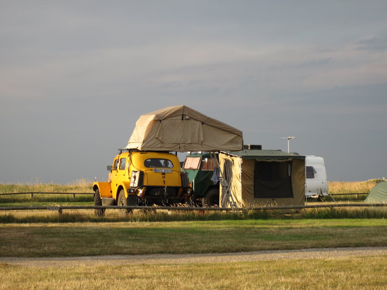 creative-03 Outdoor camping scene with a classic car, roof tent, and field backdrop, ideal for travel enthusiasts.